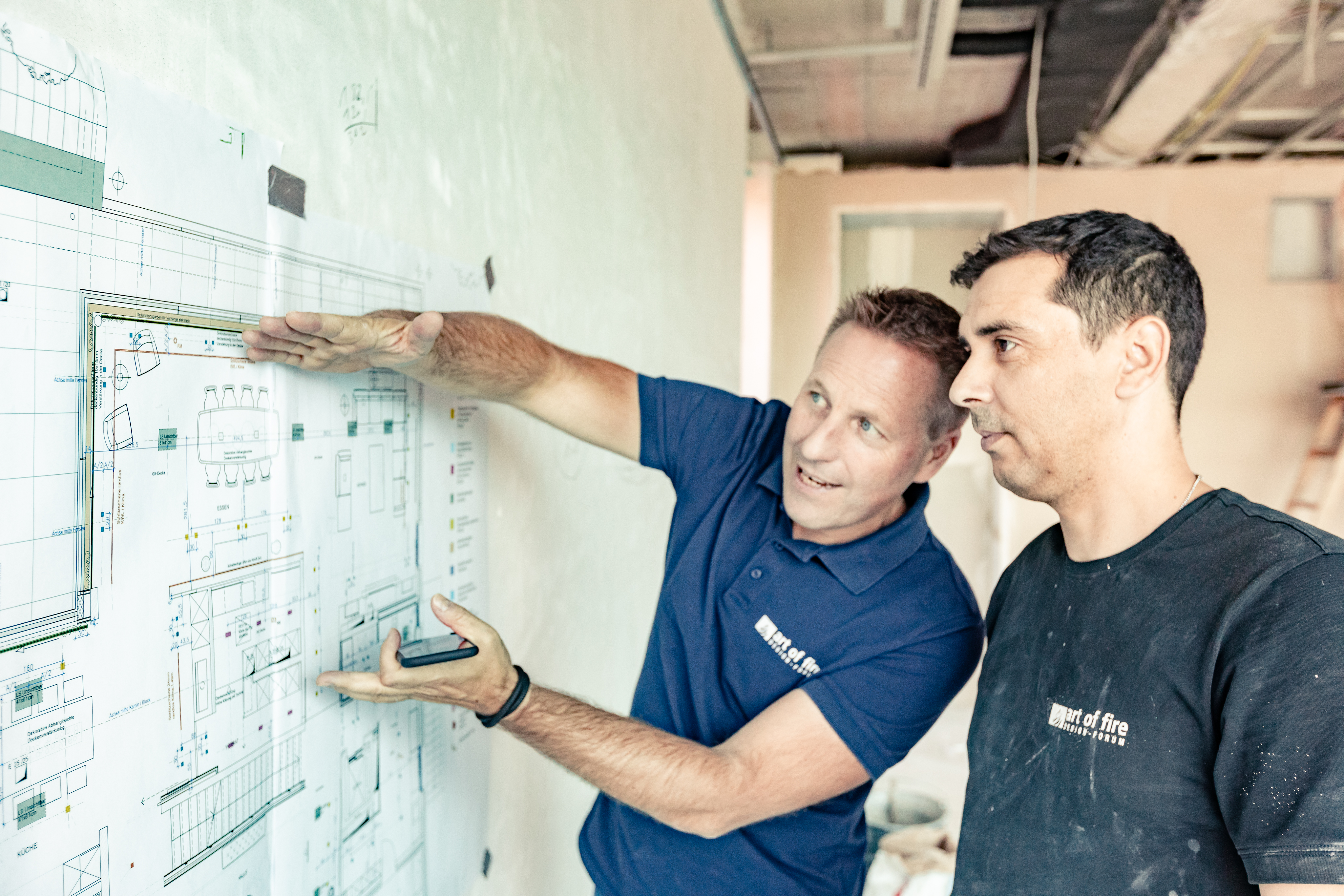 Zwei Mitarbeitende schauen sich, in einer Wohnung die noch im Aufbau ist, einen Wohnungsplan an.