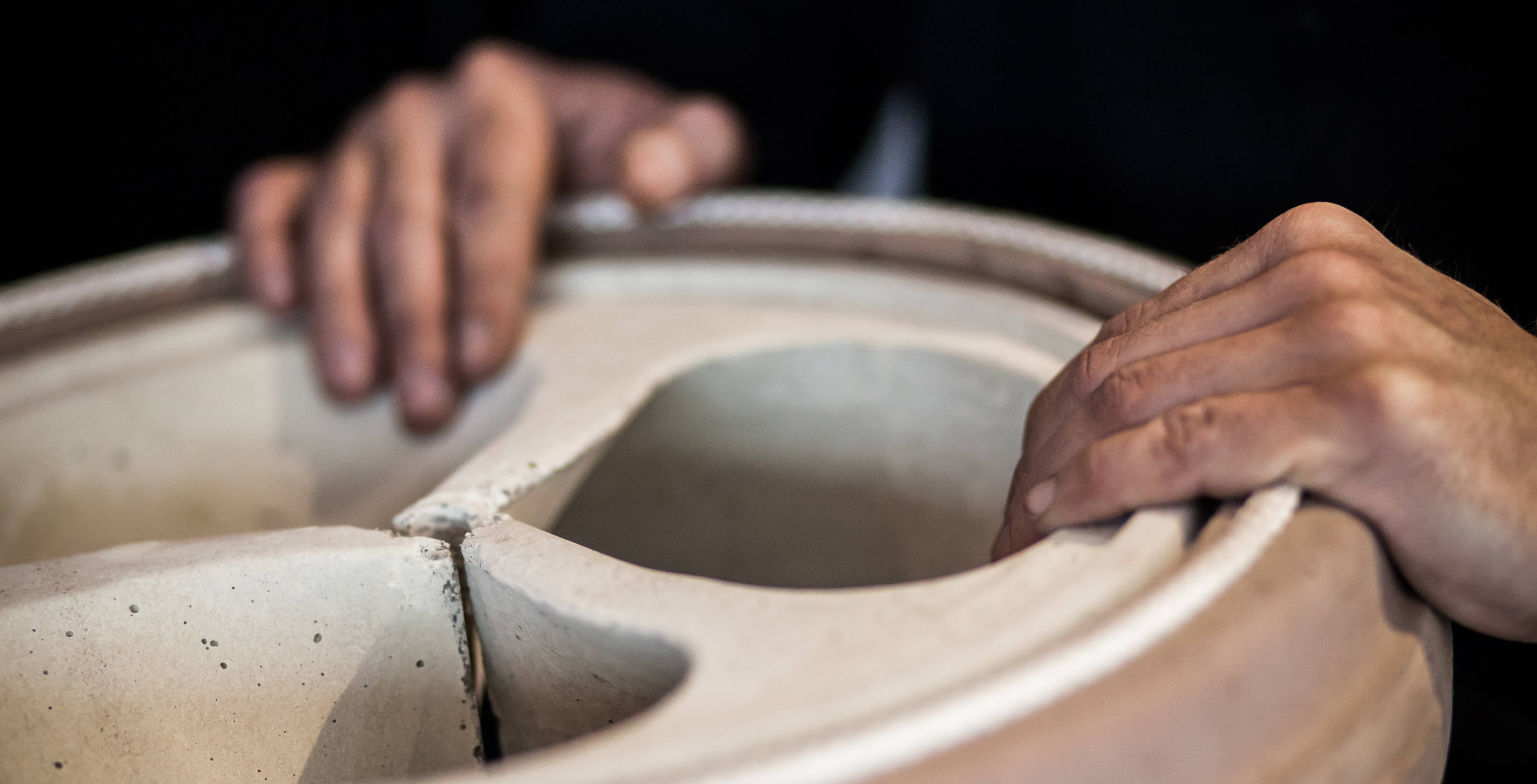 Zu sehen ist eine Person welche präzise geformte keramische Bauteile eines Ofens oder Kamins.